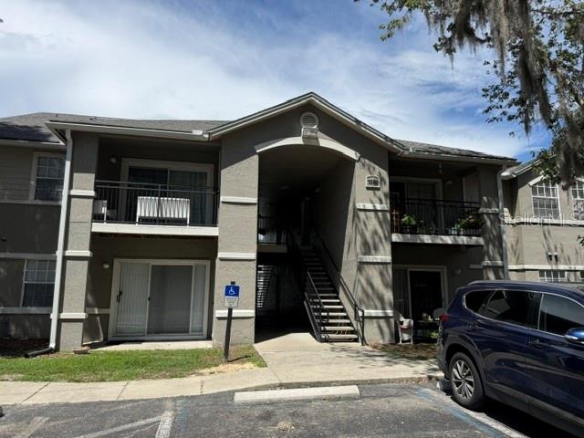 A two-story apartment building features gray stucco siding, balconies, and a central stairwell — 3705 SW 27TH STREET UNIT 1015, GAINESVILLE, FL
