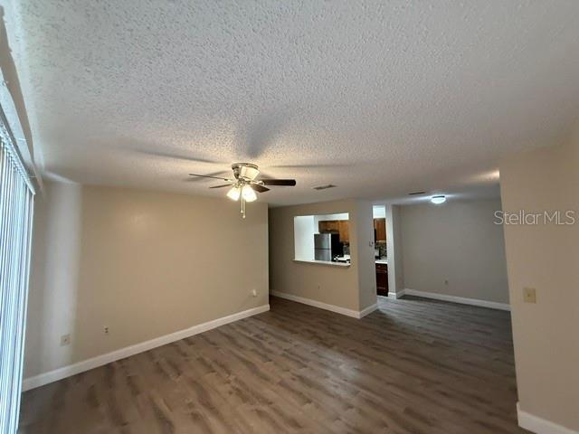 An open-concept living area features wood-look flooring, a ceiling fan, and a kitchen pass-through window — 3705 SW 27TH STREET UNIT 1015, GAINESVILLE, FL