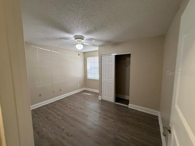 An empty bedroom features light-colored walls, wood-look flooring, a ceiling fan, and a closet — 3705 SW 27TH STREET UNIT 1015, GAINESVILLE, FL