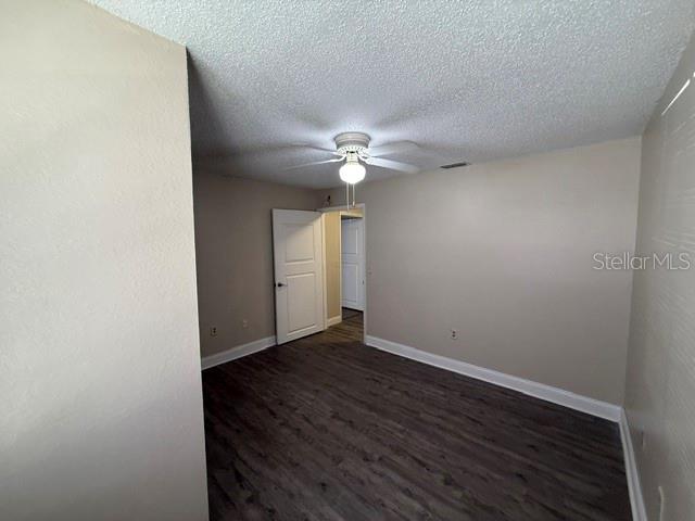 An empty room features light-colored walls, dark wood-look flooring, and a ceiling fan — 3705 SW 27TH STREET UNIT 1015, GAINESVILLE, FL