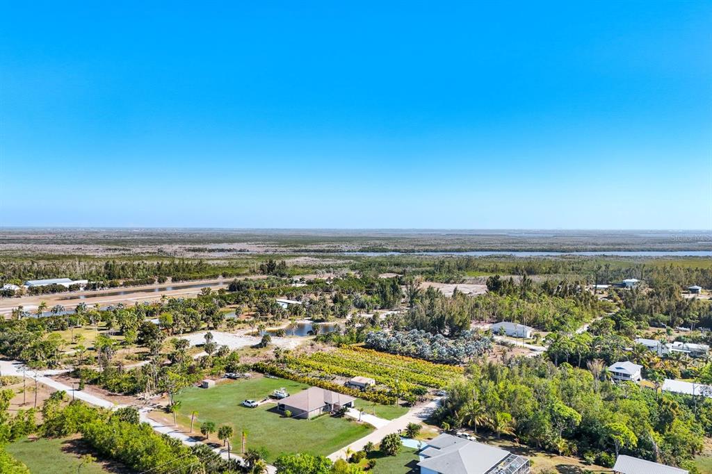 An aerial view shows a rural residential area with houses, trees, and a distant waterway — 4442 COURTNEY ROAD, ST JAMES CITY, FL