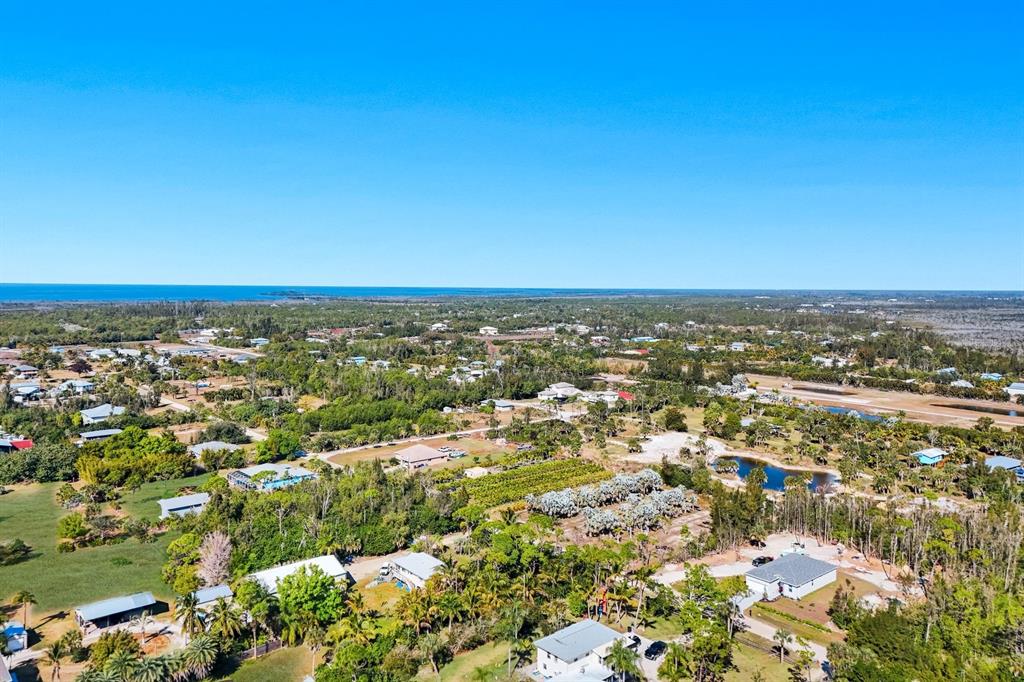 An aerial view shows a rural residential area with scattered houses, dense vegetation, and a pond — 4442 COURTNEY ROAD, ST JAMES CITY, FL