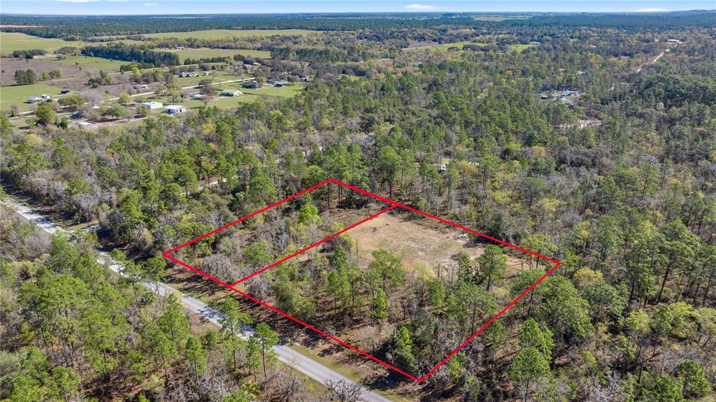 An aerial view shows a rural property with scattered trees, dirt roads, and small buildings — 9097 N PEEWEE POINT, DUNNELLON, FL