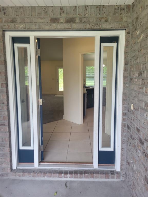 A view through an open front door into a home with tiled flooring and brick exterior — 25 BARRINGTON DRIVE, PALM COAST, FL