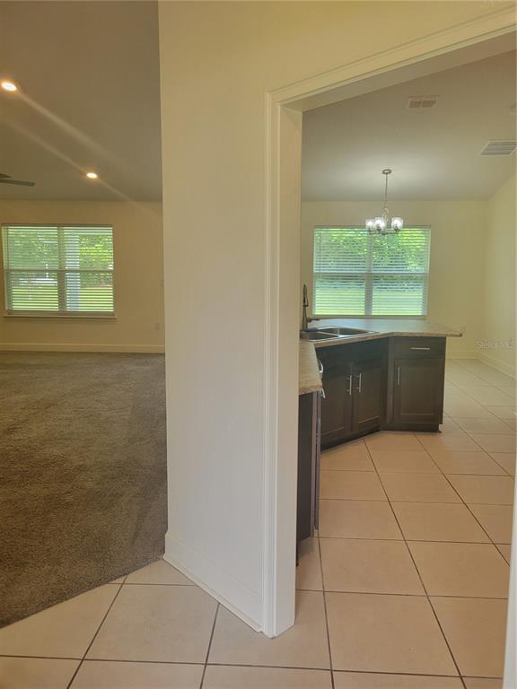 A view from a doorway shows a carpeted living area and a tiled kitchen — 25 BARRINGTON DRIVE, PALM COAST, FL