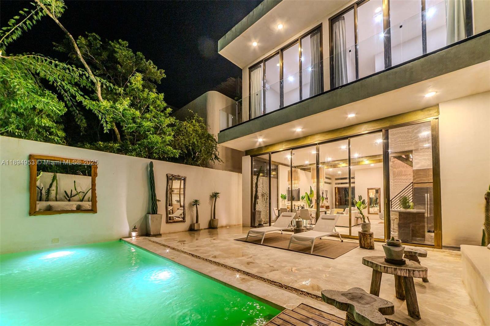 A modern two-story house features a swimming pool, patio lounge chairs, and large glass doors — 25 Calle Tulipan # 25, TX 77760, TX
