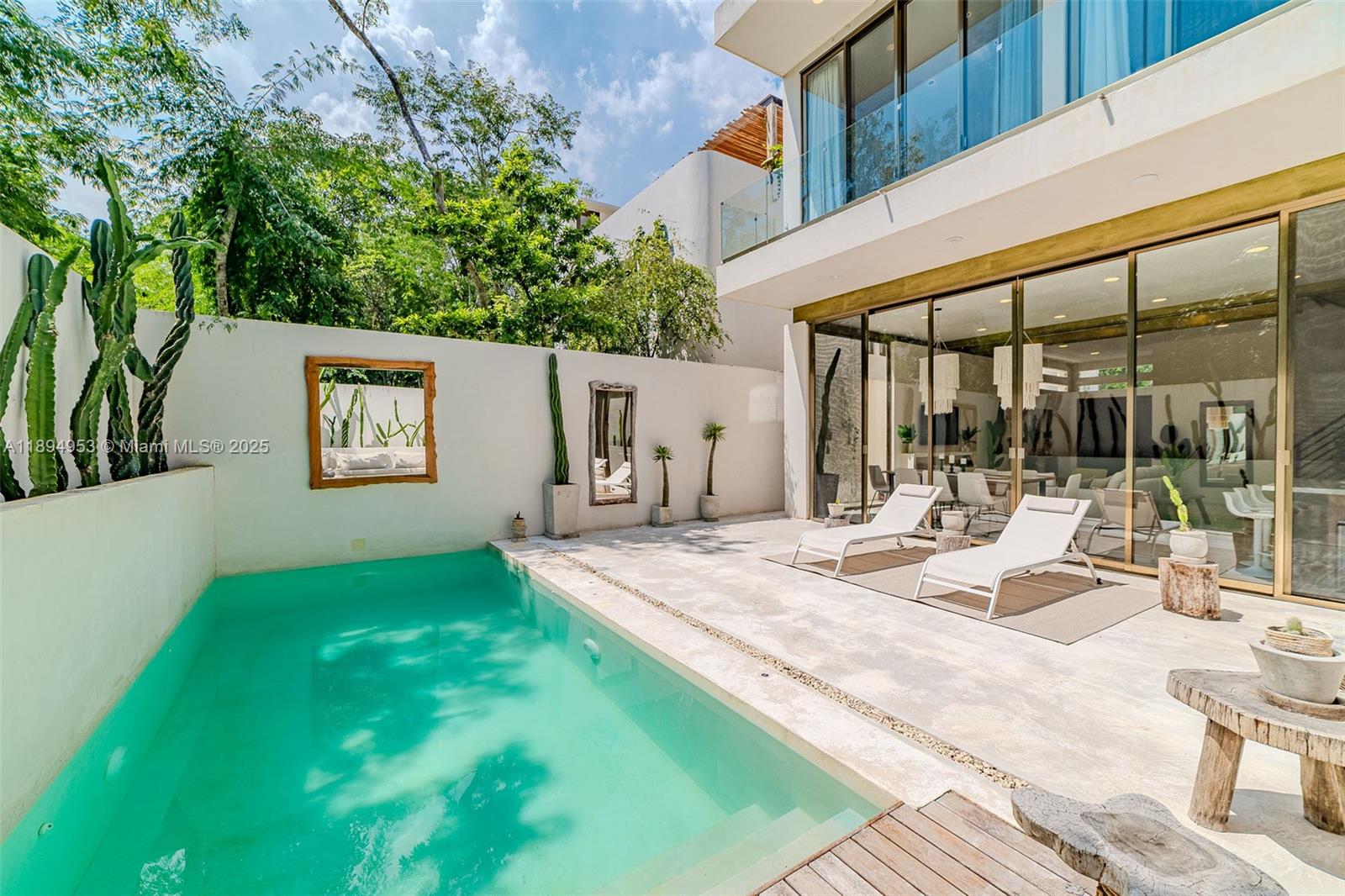 A modern patio features a swimming pool, two lounge chairs, and cacti against a white wall — 25 Calle Tulipan # 25, TX 77760, TX