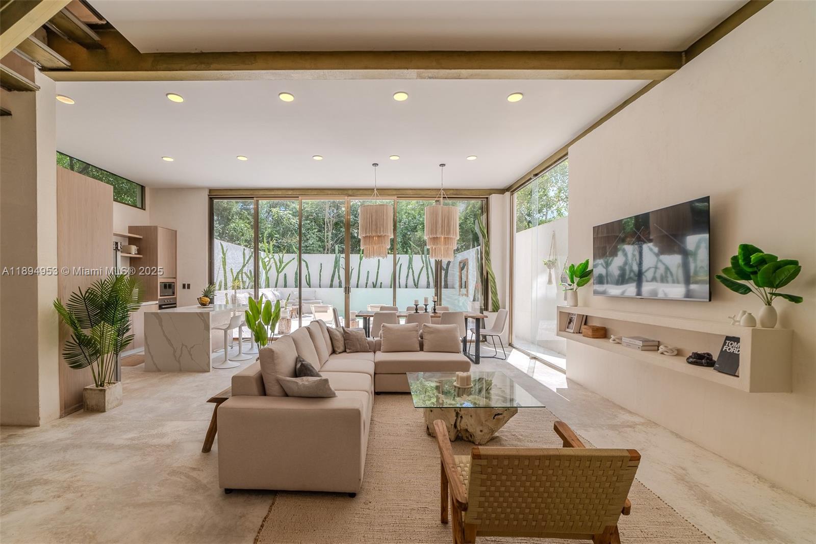 This open-concept living and dining area features a neutral color palette, stone flooring, and floor-to-ceiling windows — 25 Calle Tulipan # 25, TX 77760, TX