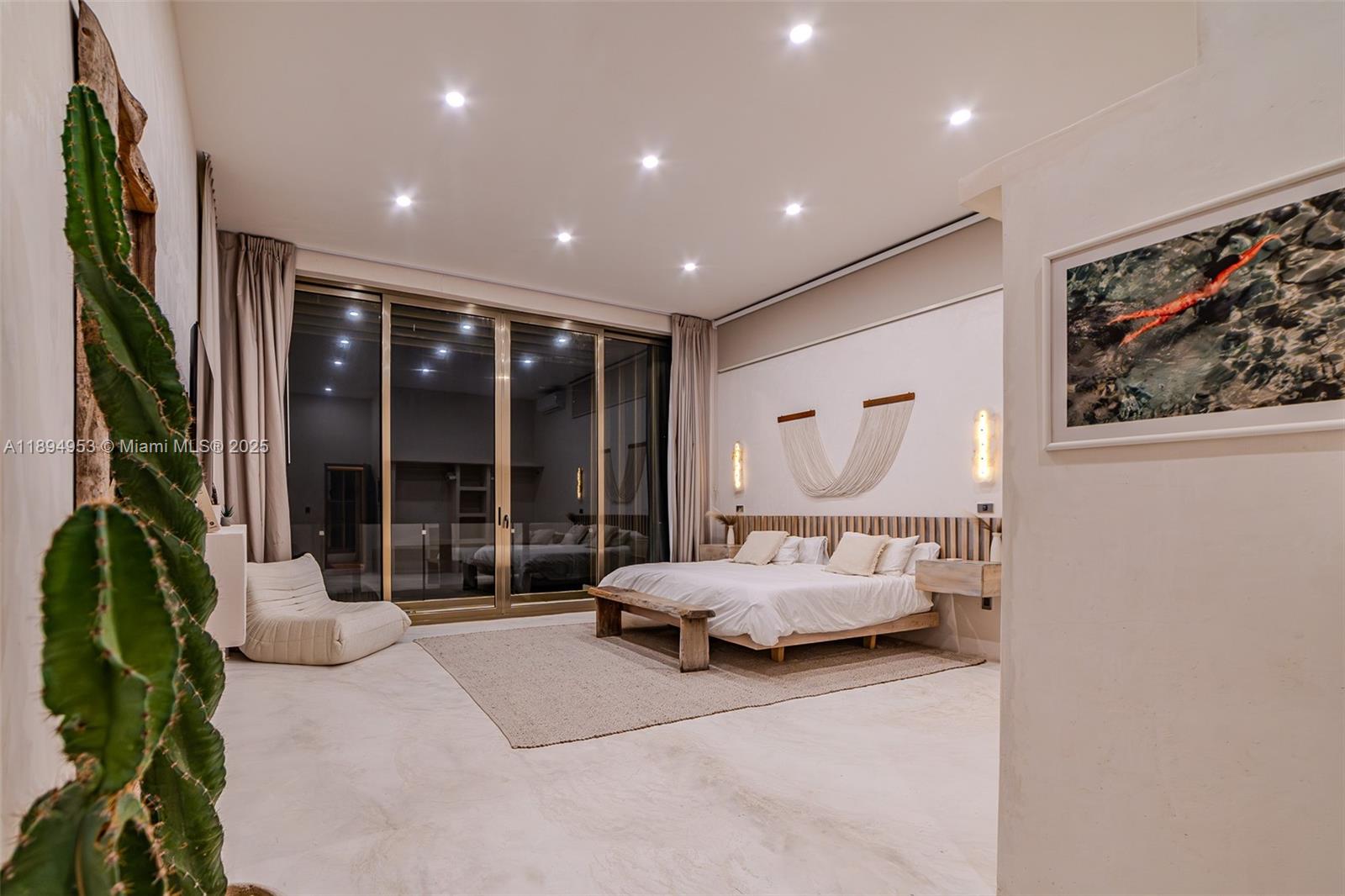 A modern bedroom features a platform bed, a large cactus, and floor-to-ceiling glass doors — 25 Calle Tulipan # 25, TX 77760, TX