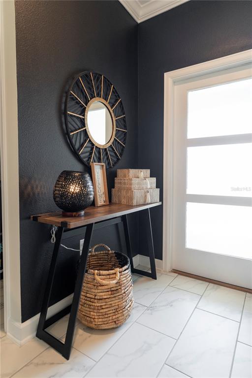 An entryway features a console table, a round mirror, and a basket against a black wall — 1184 CHALLENGE DRIVE, DAVENPORT, FL