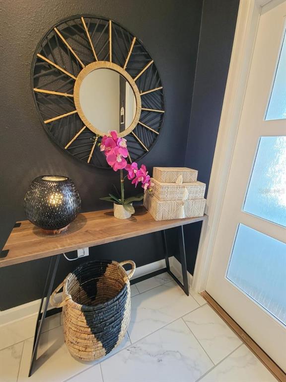 A modern entryway features a console table, a round sunburst mirror, and a decorative basket — 1184 CHALLENGE DRIVE, DAVENPORT, FL