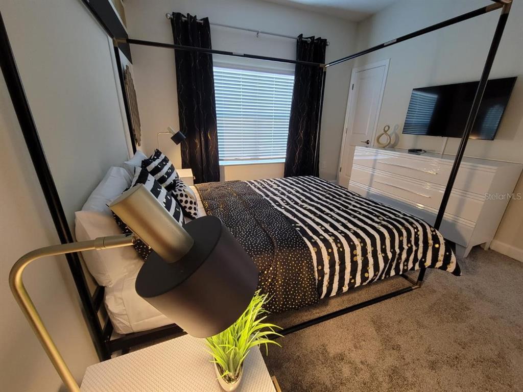 A bedroom features a black canopy bed, striped bedding, and a white dresser with a television — 1184 CHALLENGE DRIVE, DAVENPORT, FL