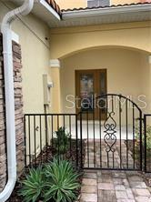 A wrought iron gate leads to a paved entryway with a front door and stone siding — 2095 VELVET LEAF DRIVE, OCOEE, FL