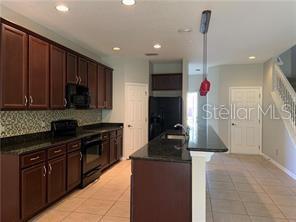 A kitchen with dark wood cabinets, granite countertops, and a breakfast bar island — 2095 VELVET LEAF DRIVE, OCOEE, FL
