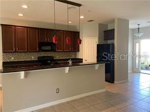 A kitchen features dark wood cabinets, a breakfast bar, and a black refrigerator — 2095 VELVET LEAF DRIVE, OCOEE, FL