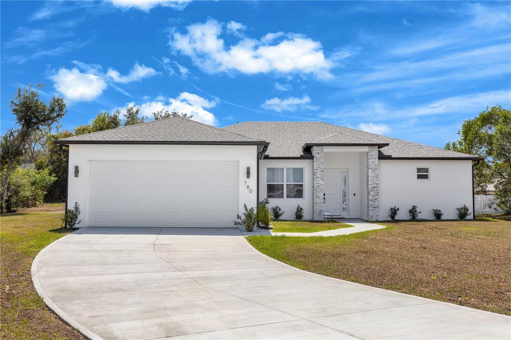 A white single-story house with a two-car garage and stone accents on the front porch — 780 KANGAROO COURT, DELTONA, FL