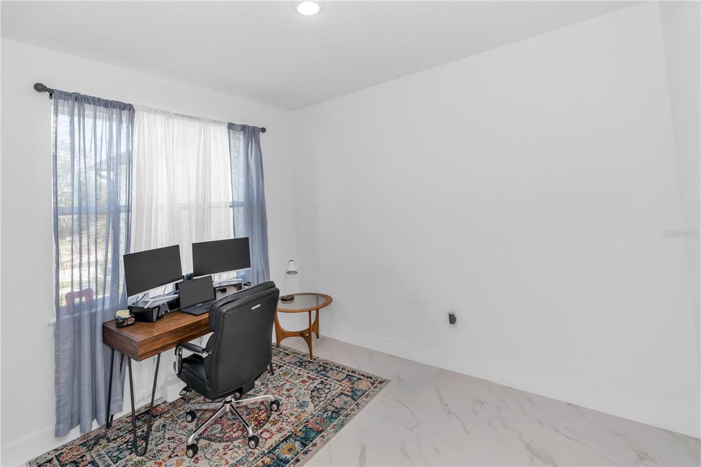 A home office with a desk, dual monitors, a chair, and a patterned area rug — 780 KANGAROO COURT, DELTONA, FL