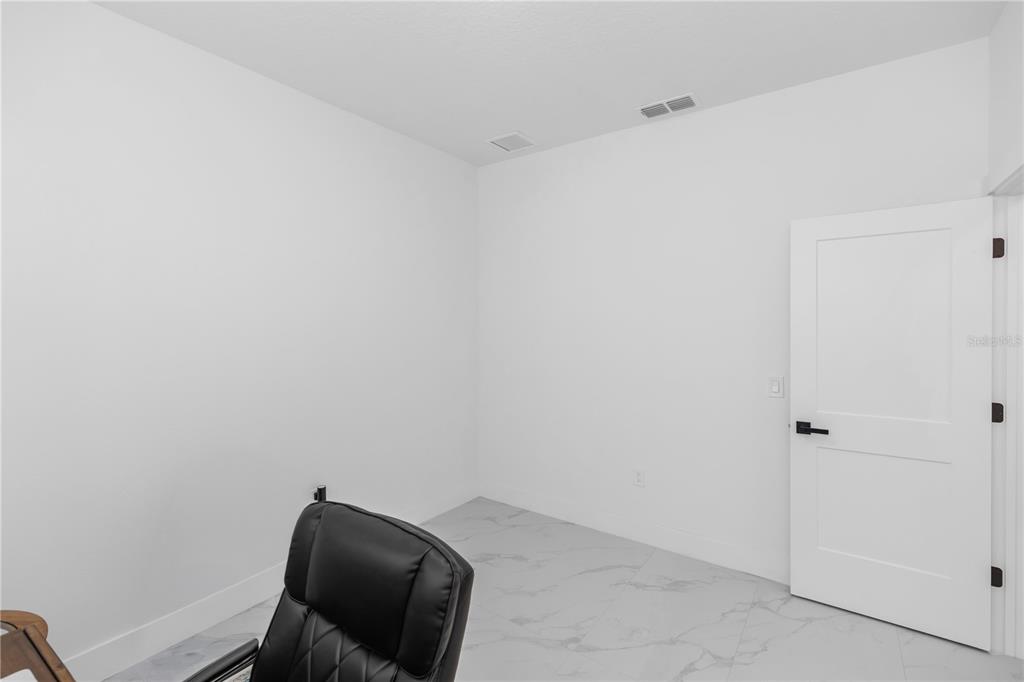 A bright, empty room features white walls, light-colored tile flooring, and a white interior door — 780 KANGAROO COURT, DELTONA, FL