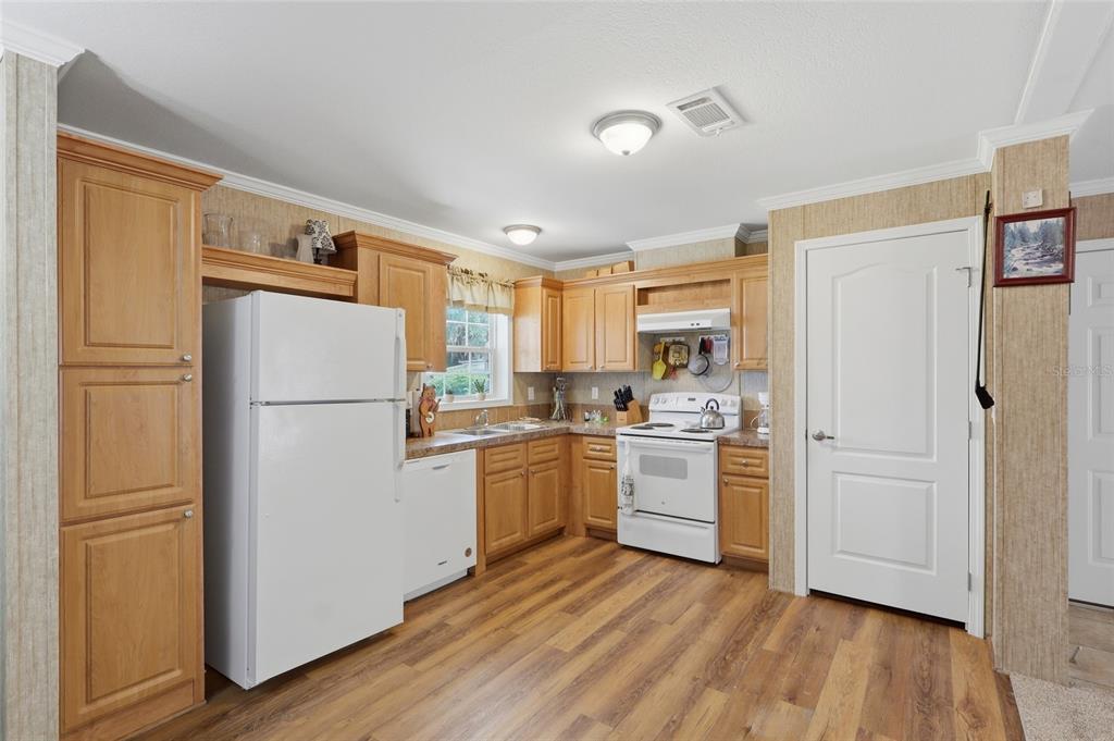 A kitchen features light wood cabinets, white appliances, and wood-look flooring — 38745 NEW JERSEY AVENUE, ZEPHYRHILLS, FL
