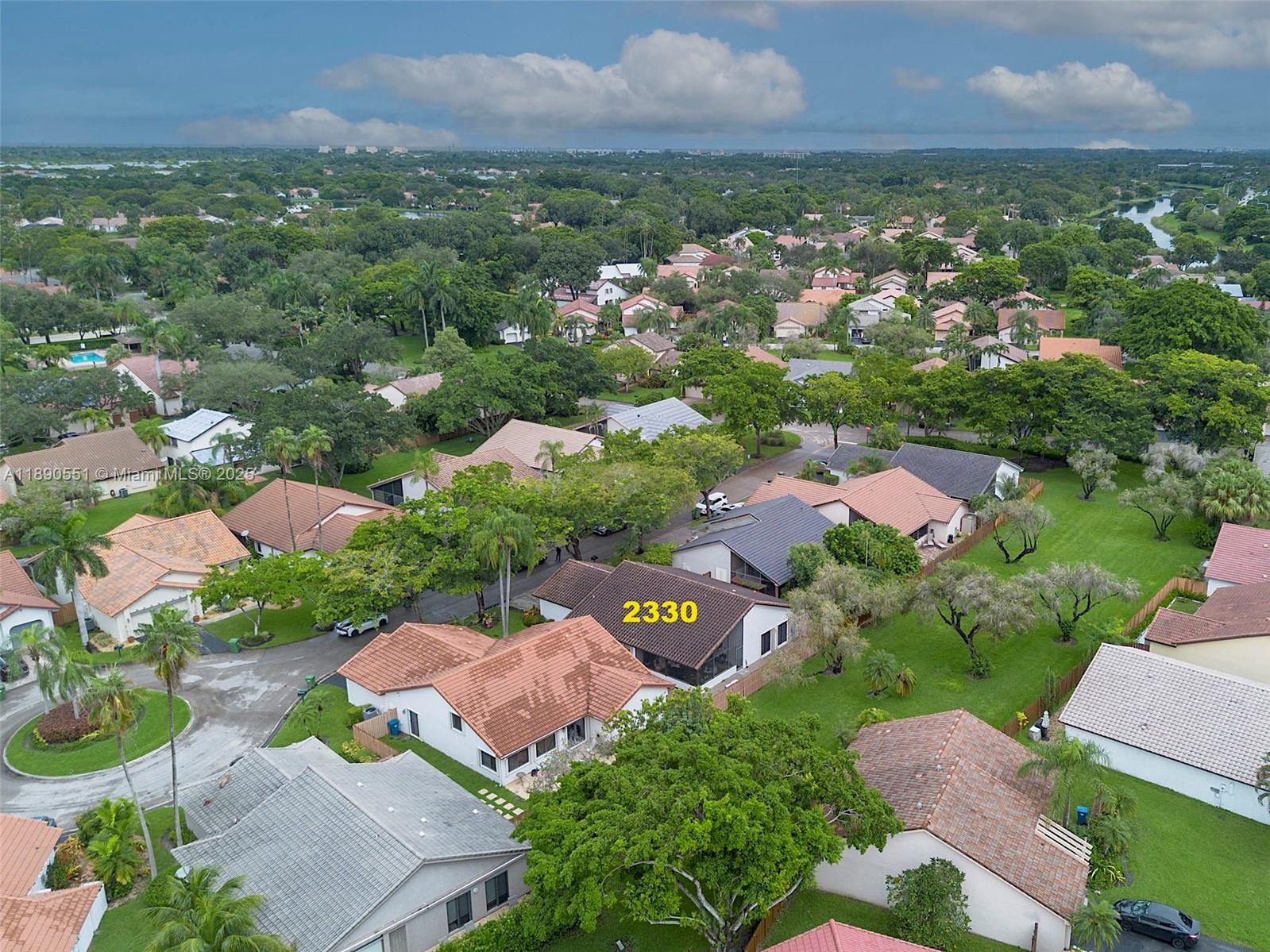 An aerial view shows a suburban neighborhood with single-family homes and lush green trees — 2330 Dover, Weston FL 33326, WESTON, FL