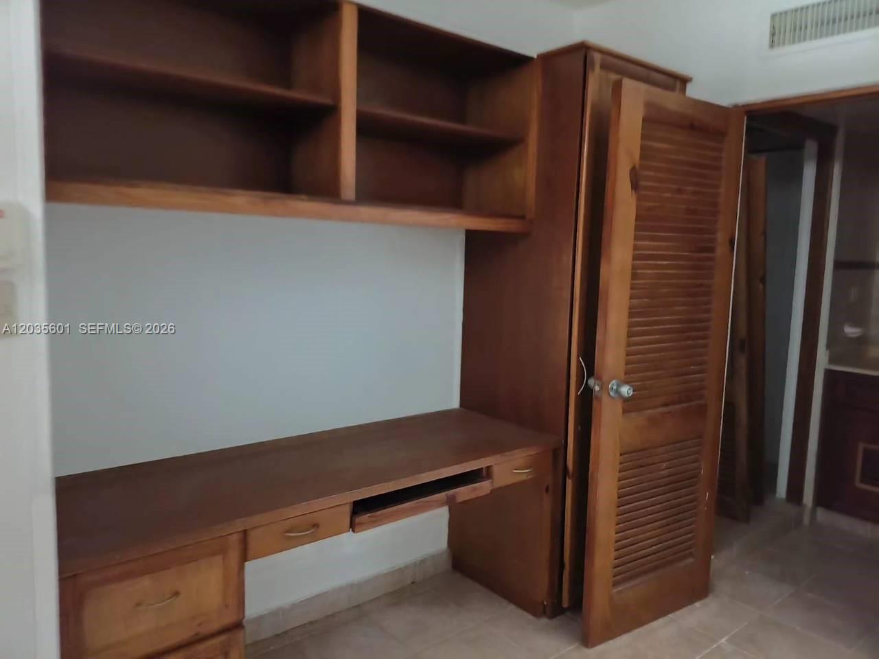 A wooden desk with built-in shelving and a louvered closet door in a room — 1 cap cana # 0, FL