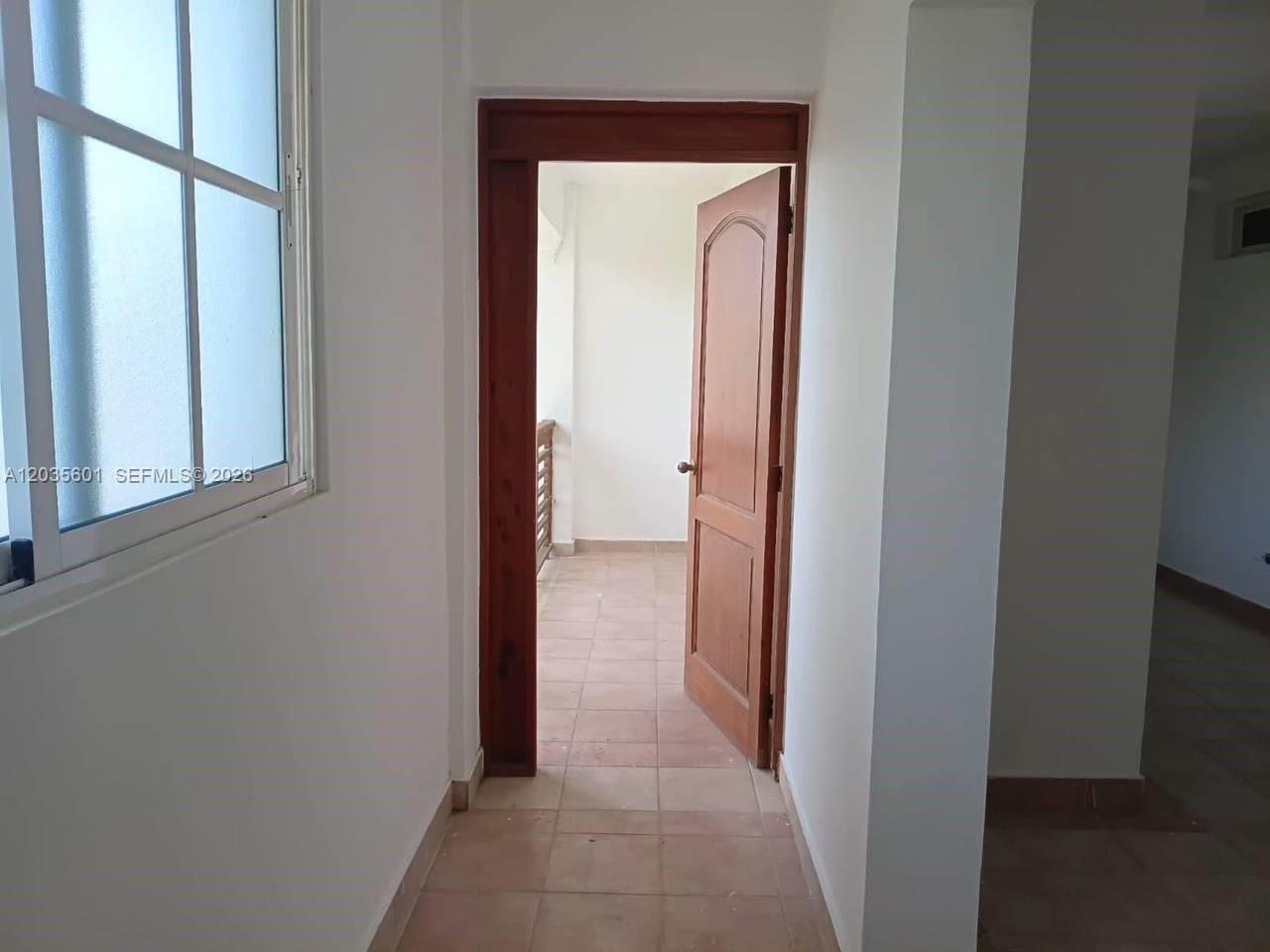 A tiled hallway leads through an open wooden door to a small balcony — 1 cap cana # 0, FL