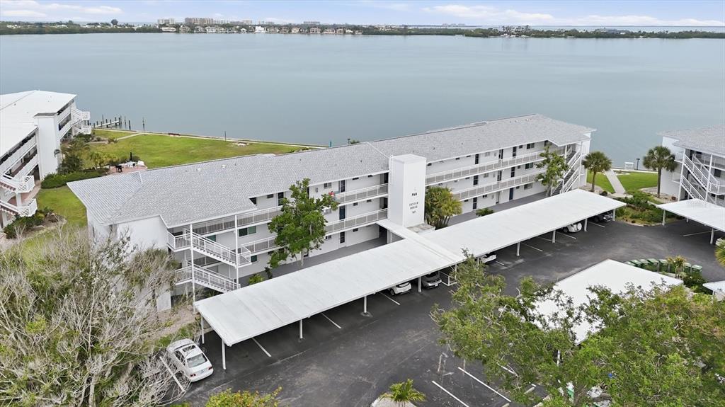 An aerial view shows a multi-story apartment building with covered parking and waterfront access — 769 JOHN RINGLING BOULEVARD UNIT 4, SARASOTA, FL