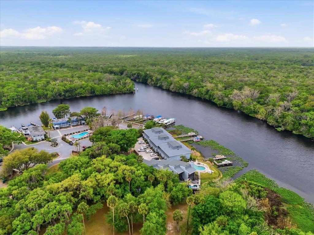An aerial view shows a waterfront resort with multiple buildings, swimming pools, and boat docks — 2329 RIVER RIDGE ROAD UNIT 2, DELAND, FL