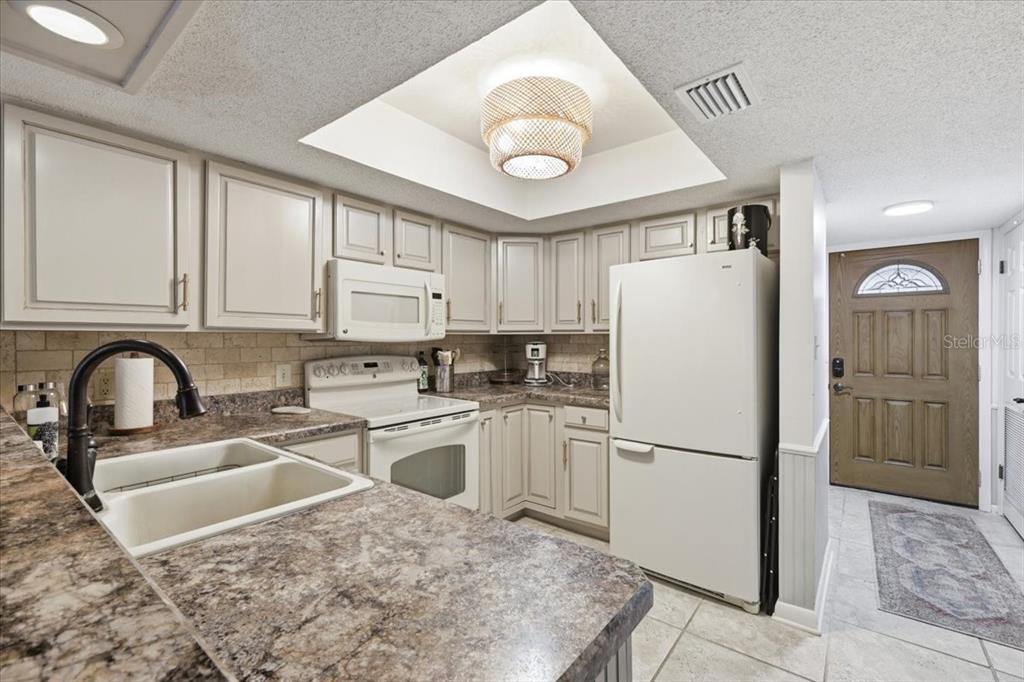 A kitchen features light-colored cabinets, a white refrigerator, a double sink, and a tray ceiling — 2329 RIVER RIDGE ROAD UNIT 2, DELAND, FL