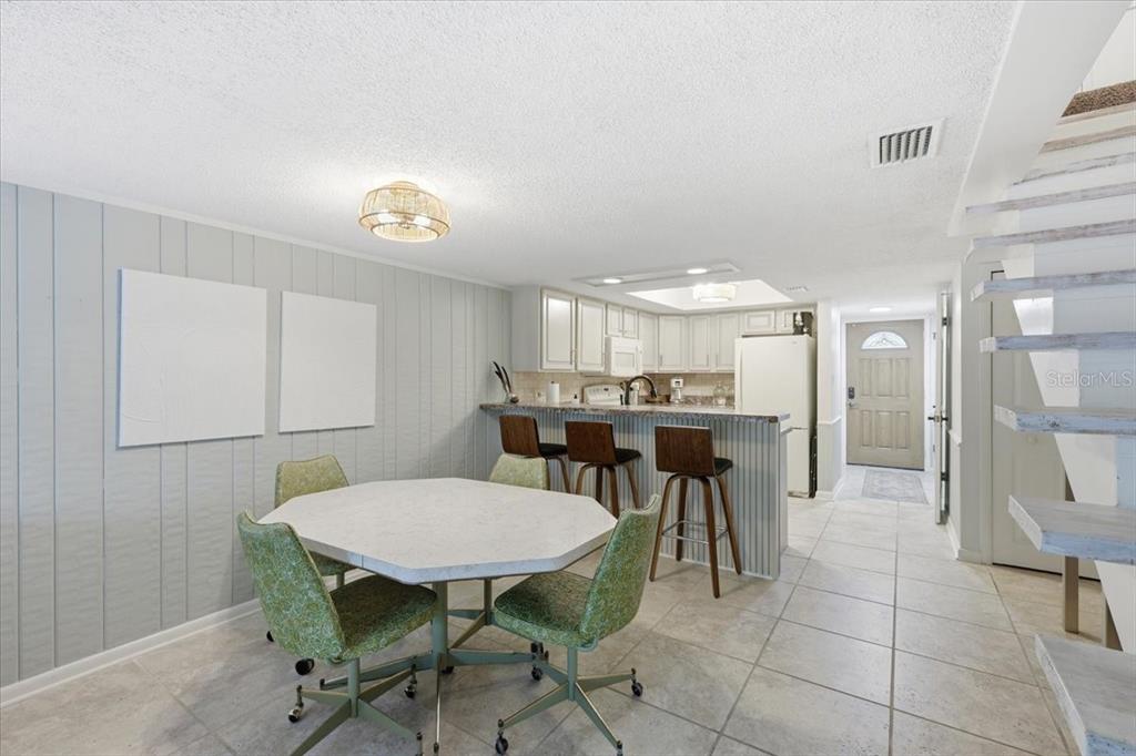 A dining area with a table and chairs sits before a kitchen with bar seating — 2329 RIVER RIDGE ROAD UNIT 2, DELAND, FL