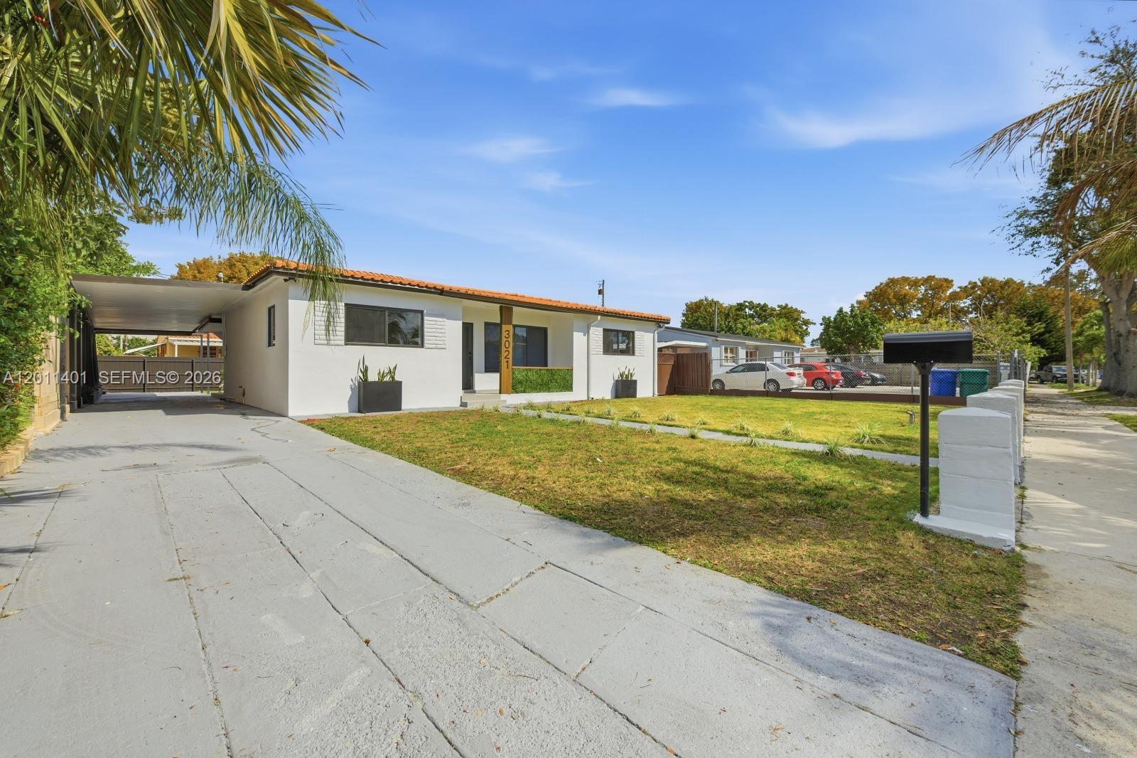 A single-story white house features a carport, a front lawn, and a paved driveway — 3021 SW 12th St, Miami FL 33135, MIAMI, FL