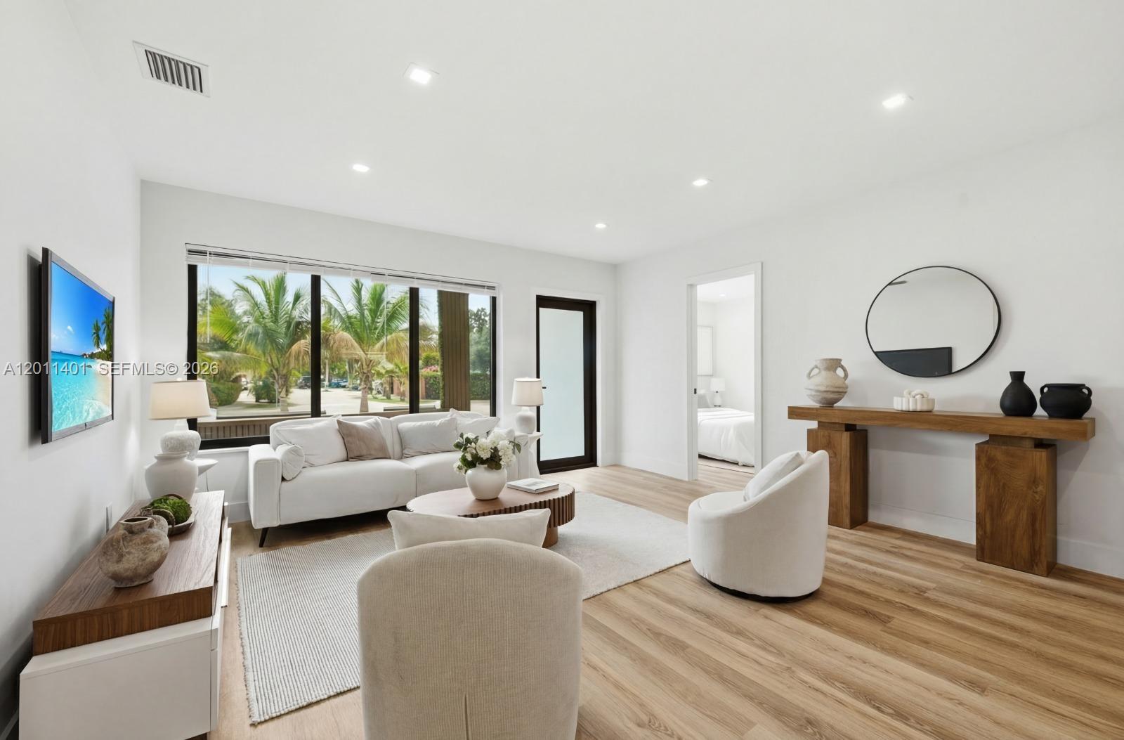 A bright living room features white furniture, a wooden console table, and large windows — 3021 SW 12th St, Miami FL 33135, MIAMI, FL