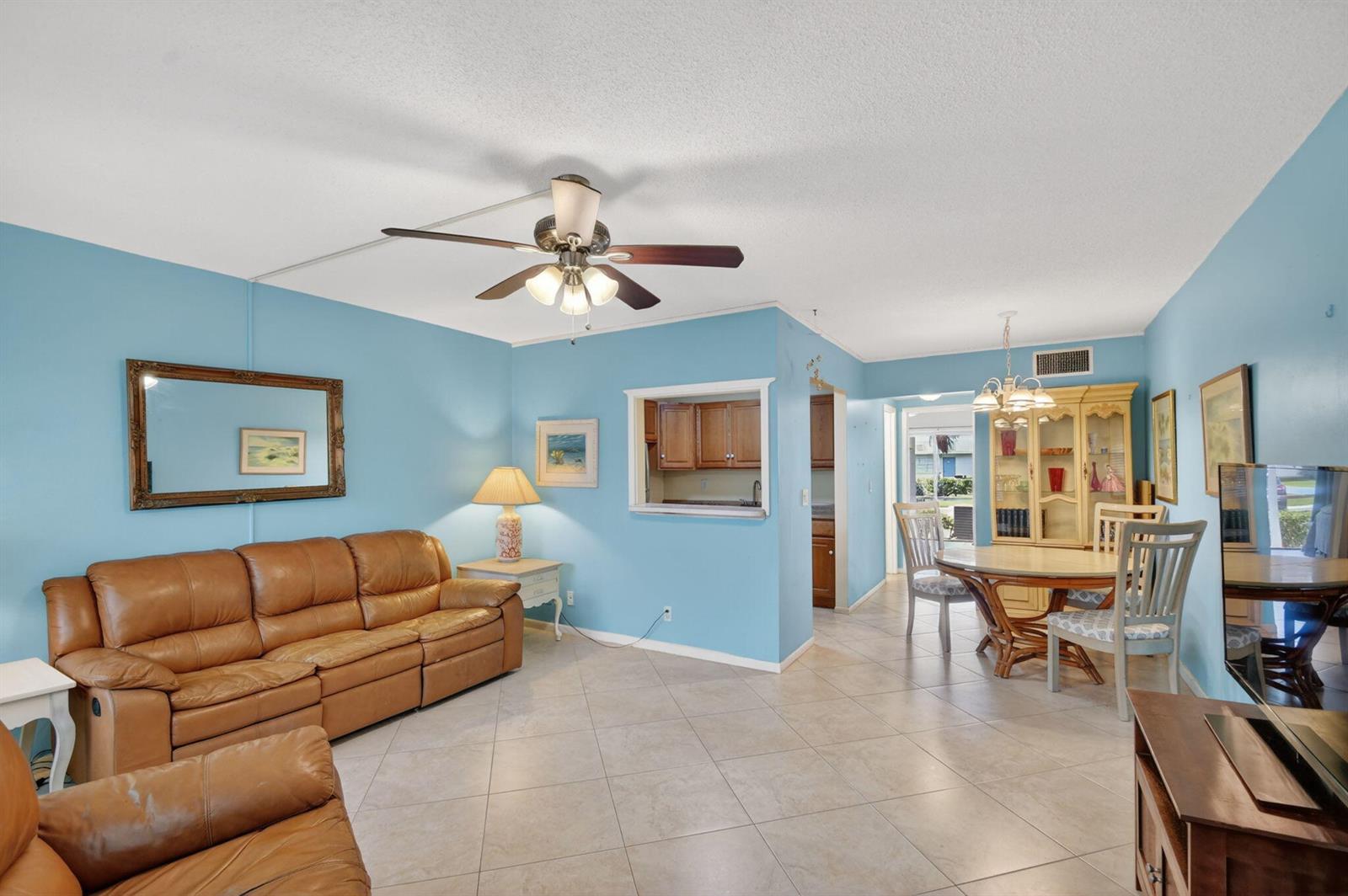 A living and dining area with light blue walls, tile floors, and brown leather furniture — 370 Horizon Street E # 107, Boynton Beach FL 33435, BOYNTON BEACH, FL