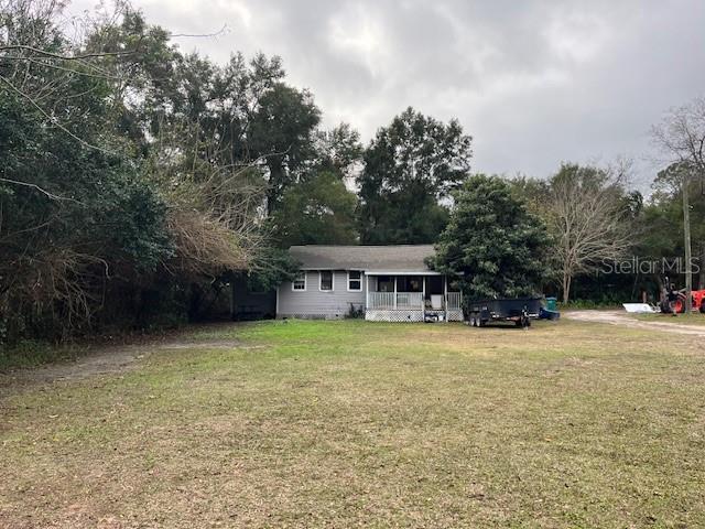 A single-story house with gray siding sits on a large, grassy lot with trees — 13730 NW 140TH STREET, ALACHUA, FL