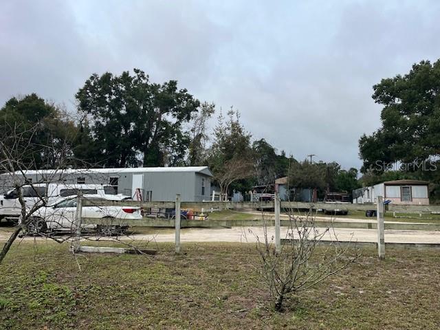 A white fence encloses a gravel lot with mobile homes and parked vehicles — 13730 NW 140TH STREET, ALACHUA, FL