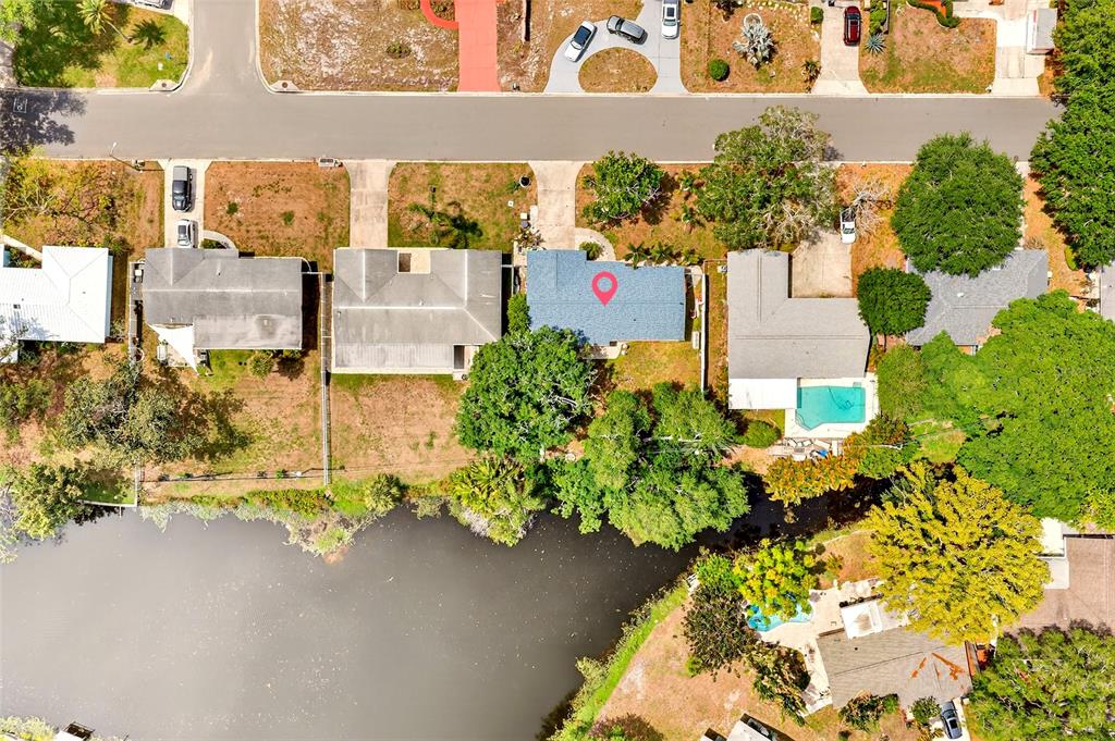 An aerial view shows a residential neighborhood with houses, driveways, trees, and a waterfront area — 1565 S EVERGREEN AVENUE, CLEARWATER, FL