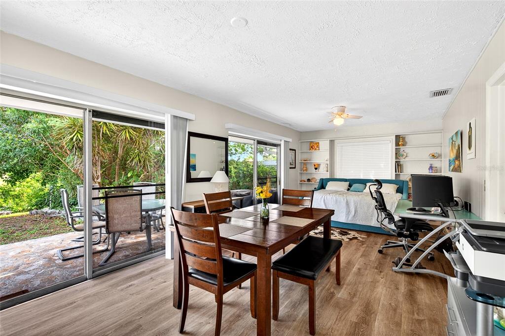 A dining area with a wood table and chairs opens to a patio through sliding doors — 1565 S EVERGREEN AVENUE, CLEARWATER, FL