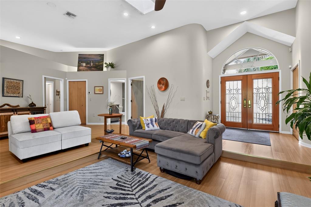 A living room features a sunken floor, a gray sectional sofa, and double front doors — 4424 FRIAR TUCK LANE, SARASOTA, FL