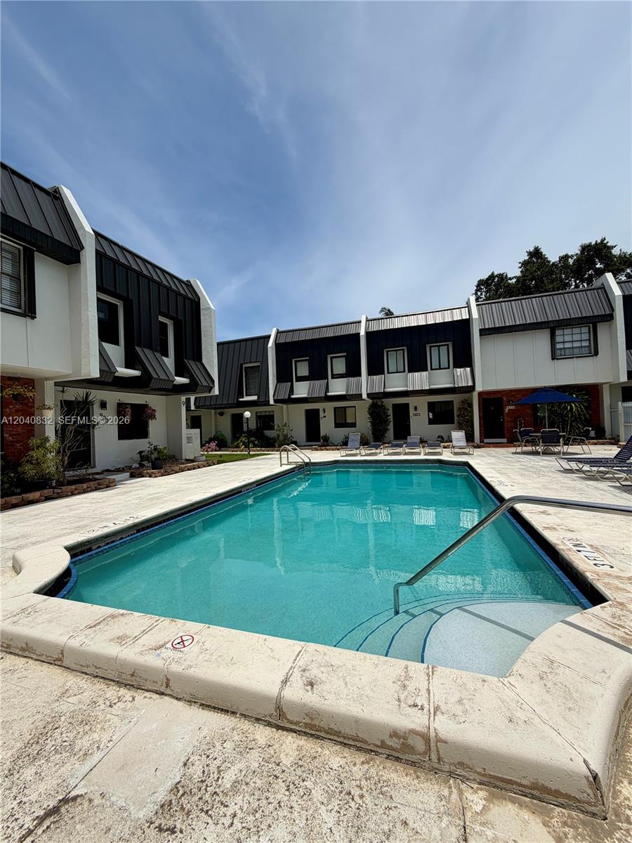 A rectangular swimming pool sits in a courtyard surrounded by two-story townhouses with dark roofs — 6667 Miller Dr # 15, South Miami FL 33155, SOUTH MIAMI, FL