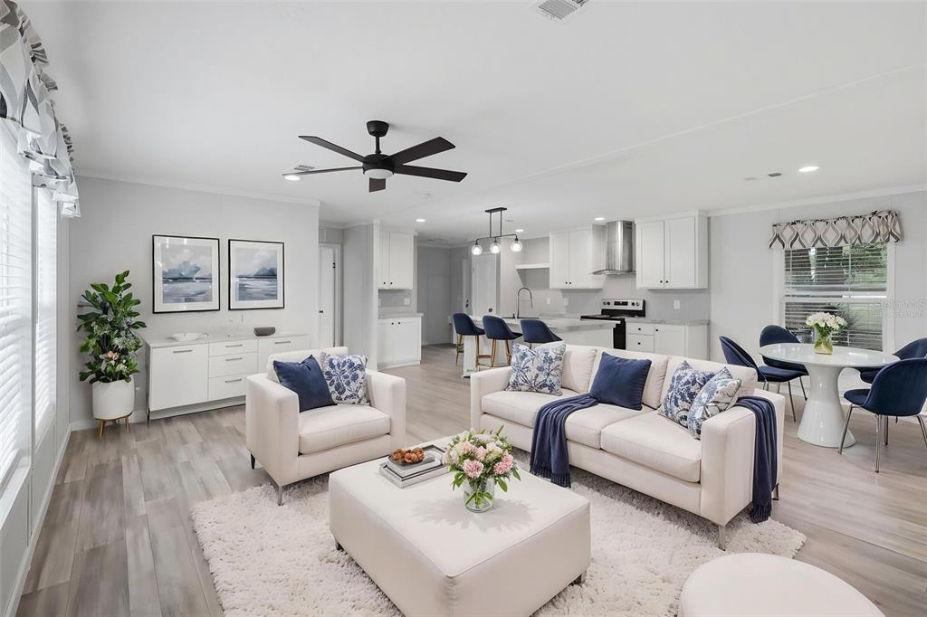 An open-concept living room and kitchen featuring white cabinetry, light wood flooring, and blue accents — 781 BAYOU DRIVE, CASSELBERRY, FL