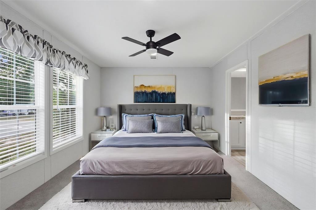A bedroom features a gray upholstered bed, two nightstands, a ceiling fan, and wall art — 781 BAYOU DRIVE, CASSELBERRY, FL