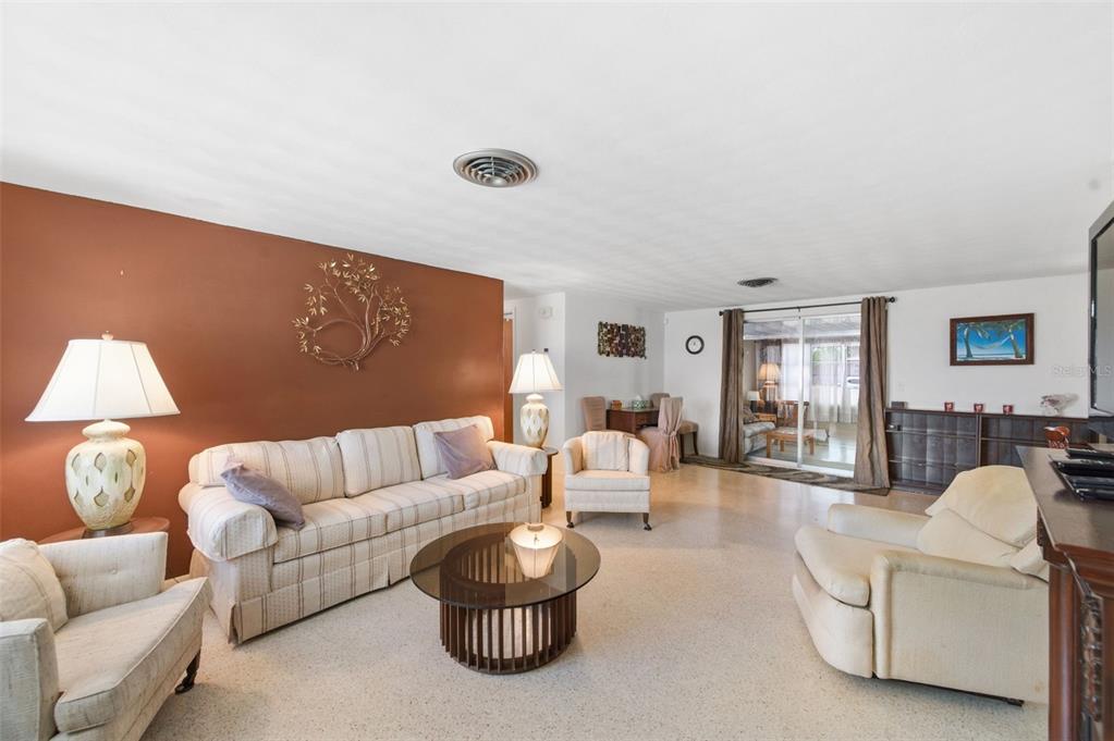 A living room features a striped sofa, two armchairs, a coffee table, and brown walls — 3904 REDWOOD DRIVE, HOLIDAY, FL