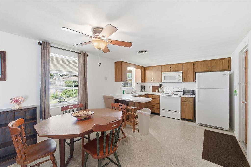 A kitchen and dining area with wooden cabinets, white appliances, and a wooden dining table — 3904 REDWOOD DRIVE, HOLIDAY, FL