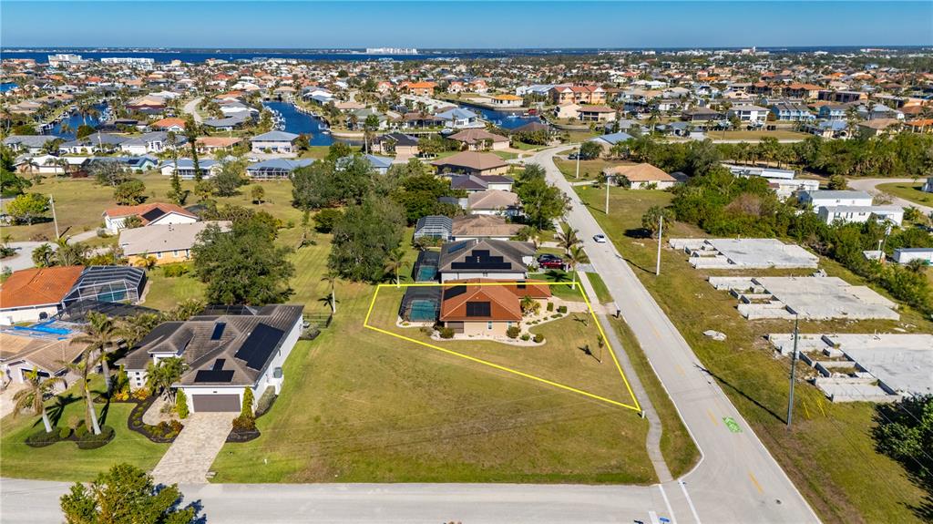 An aerial view shows a house with a pool and solar panels on a large lot — 1300 TUSCANY DRIVE, PUNTA GORDA, FL