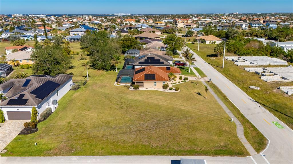 An aerial view shows a residential neighborhood with houses featuring solar panels and pools — 1300 TUSCANY DRIVE, PUNTA GORDA, FL