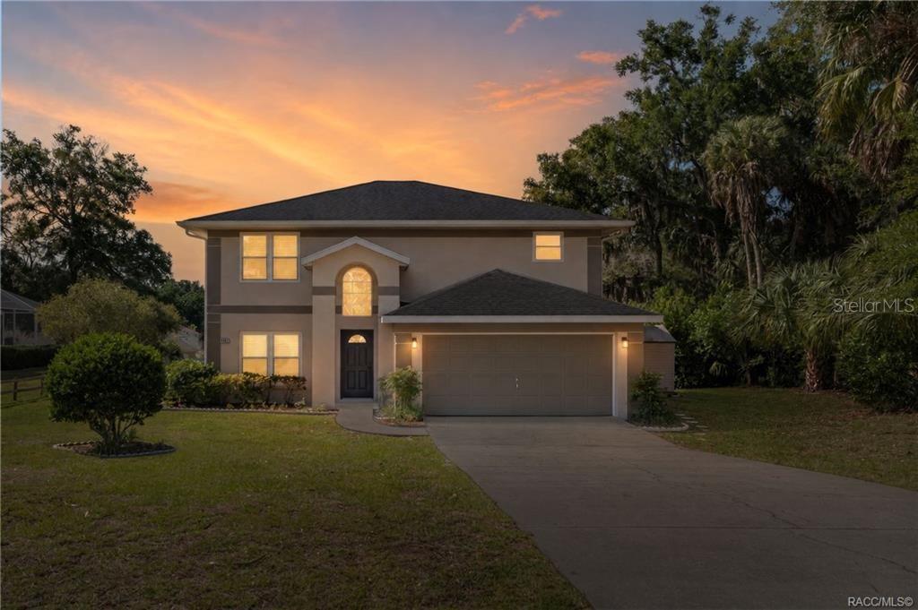 A two-story house with a beige exterior, a two-car garage, and a concrete driveway — 4482 E AVOCET COURT, INVERNESS, FL