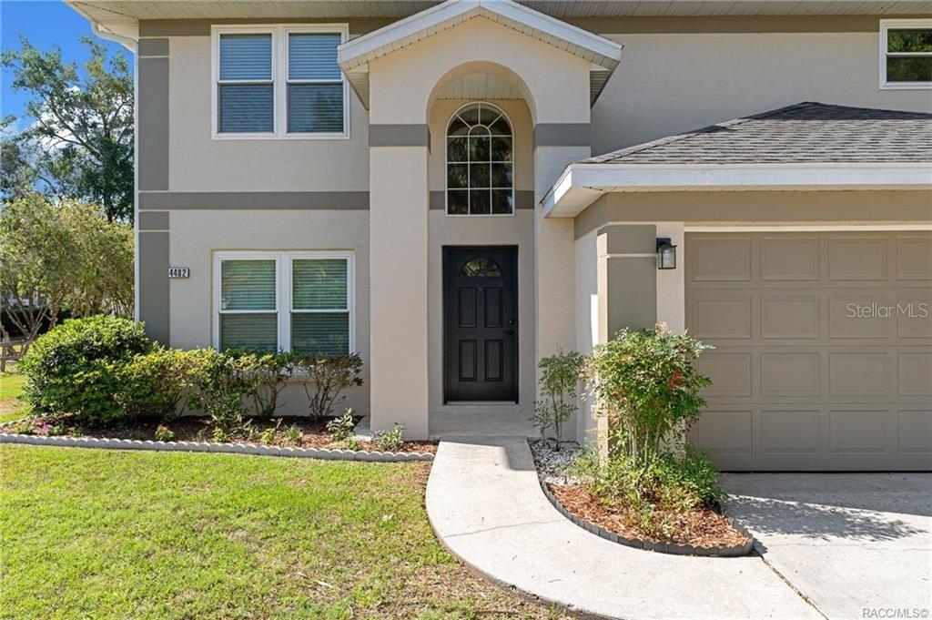 The exterior of a two-story house features a black front door, arched window, and garage — 4482 E AVOCET COURT, INVERNESS, FL