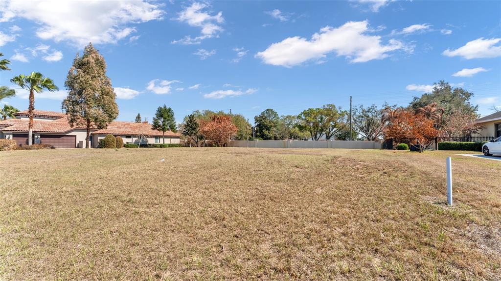 A vacant, grassy residential lot sits in front of a house and a perimeter wall — 4410 EMERALD PALMS LANE, WINTER HAVEN, FL