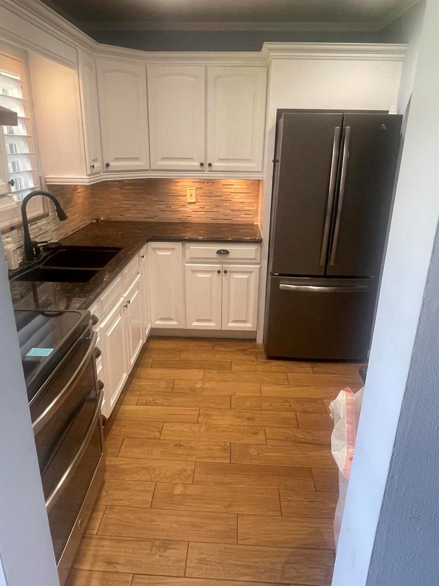 A kitchen features white cabinets, dark countertops, a black refrigerator, and wood-look tile flooring — 752 Lori Drive # 223, Palm Springs FL 33461, PALM SPRINGS, FL