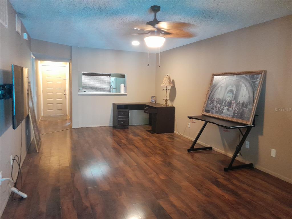 A room with wood-look flooring, a ceiling fan, a desk, and a large framed picture — 25210 NORTHLAKE DRIVE UNIT 210, SANFORD, FL